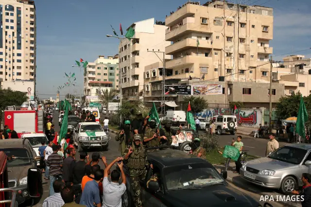 Palestinians keep watch as Hamas militants stand guard in Gaza City on October 18, 2011 as an Israeli-Palestinian prisoner swap deal gets under way. Captive Israeli soldier Gilad Shalit was today freed from five years of...