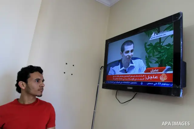 A Palestinian man watches Egypt TV Tuesday Oct 18 2011 as Israeli soldier Gilad Schalit is seen at an undisclosed location, during a pre-recorded interview released Tuesday. Schalit was moved in to Egypt from captivity i...