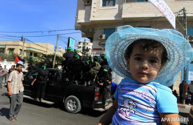 Palestinians keep watch as Hamas militants stand guard in Gaza City on October 18, 2011 as an Israeli-Palestinian prisoner swap deal gets under way. Captive Israeli soldier Gilad Shalit was today freed from five years of...