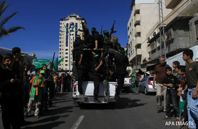 Palestinians keep watch as Hamas militants stand guard in Gaza City on October 18, 2011 as an Israeli-Palestinian prisoner swap deal gets under way. Captive Israeli soldier Gilad Shalit was today freed from five years of...