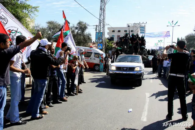 Palestinians keep watch as Hamas militants stand guard in Gaza City on October 18, 2011 as an Israeli-Palestinian prisoner swap deal gets under way. Captive Israeli soldier Gilad Shalit was today freed from five years of...