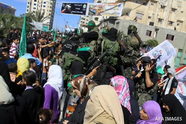 Palestinians keep watch as Hamas militants stand guard in Gaza City on October 18, 2011 as an Israeli-Palestinian prisoner swap deal gets under way. Captive Israeli soldier Gilad Shalit was today freed from five years of...