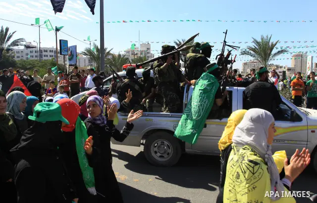 Palestinians keep watch as Hamas militants stand guard in Gaza City on October 18, 2011 as an Israeli-Palestinian prisoner swap deal gets under way. Captive Israeli soldier Gilad Shalit was today freed from five years of...