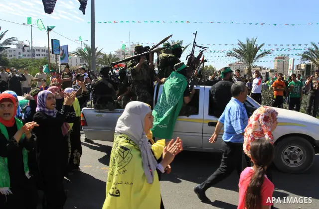 Palestinians keep watch as Hamas militants stand guard in Gaza City on October 18, 2011 as an Israeli-Palestinian prisoner swap deal gets under way. Captive Israeli soldier Gilad Shalit was today freed from five years of...