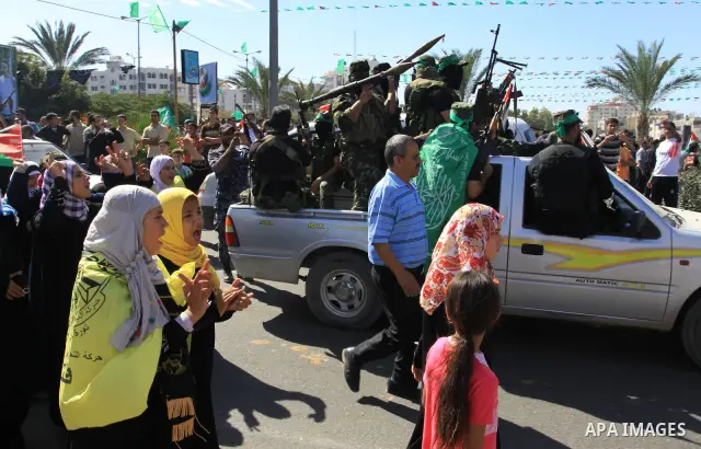 Palestinians keep watch as Hamas militants stand guard in Gaza City on October 18, 2011 as an Israeli-Palestinian prisoner swap deal gets under way. Captive Israeli soldier Gilad Shalit was today freed from five years of...