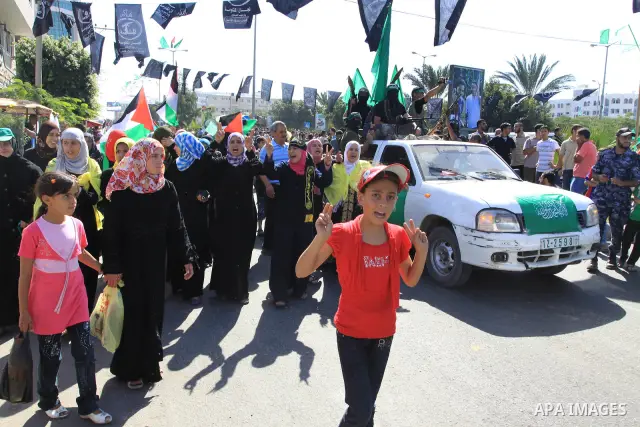 Palestinians keep watch as Hamas militants stand guard in Gaza City on October 18, 2011 as an Israeli-Palestinian prisoner swap deal gets under way. Captive Israeli soldier Gilad Shalit was today freed from five years of...