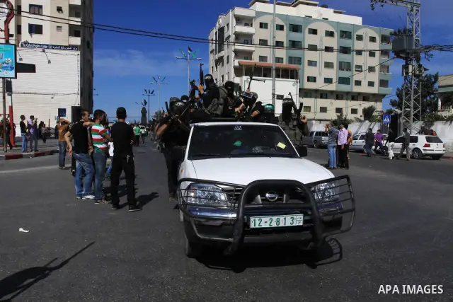 Palestinians keep watch as Hamas militants stand guard in Gaza City on October 18, 2011 as an Israeli-Palestinian prisoner swap deal gets under way. Captive Israeli soldier Gilad Shalit was today freed from five years of...