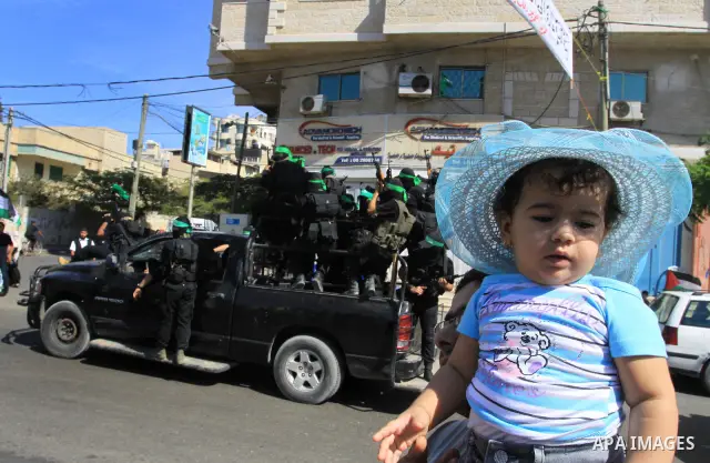 Palestinians keep watch as Hamas militants stand guard in Gaza City on October 18, 2011 as an Israeli-Palestinian prisoner swap deal gets under way. Captive Israeli soldier Gilad Shalit was today freed from five years of...