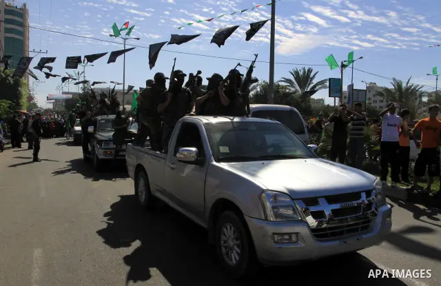 Palestinians keep watch as Hamas militants stand guard in Gaza City on October 18, 2011 as an Israeli-Palestinian prisoner swap deal gets under way. Captive Israeli soldier Gilad Shalit was today freed from five years of...