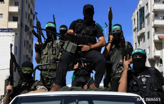 Palestinians keep watch as Hamas militants stand guard in Gaza City on October 18, 2011 as an Israeli-Palestinian prisoner swap deal gets under way. Captive Israeli soldier Gilad Shalit was today freed from five years of...