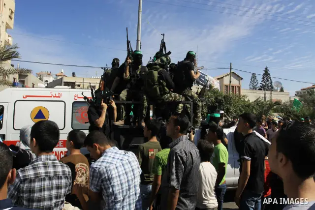 Palestinians keep watch as Hamas militants stand guard in Gaza City on October 18, 2011 as an Israeli-Palestinian prisoner swap deal gets under way. Captive Israeli soldier Gilad Shalit was today freed from five years of...