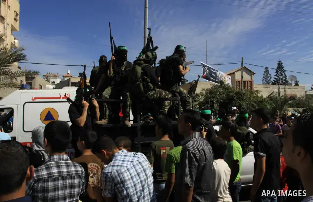 Palestinians keep watch as Hamas militants stand guard in Gaza City on October 18, 2011 as an Israeli-Palestinian prisoner swap deal gets under way. Captive Israeli soldier Gilad Shalit was today freed from five years of...