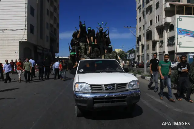 Palestinians keep watch as Hamas militants stand guard in Gaza City on October 18, 2011 as an Israeli-Palestinian prisoner swap deal gets under way. Captive Israeli soldier Gilad Shalit was today freed from five years of...