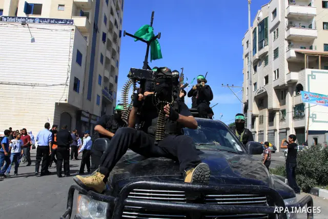 Palestinians keep watch as Hamas militants stand guard in Gaza City on October 18, 2011 as an Israeli-Palestinian prisoner swap deal gets under way. Captive Israeli soldier Gilad Shalit was today freed from five years of...