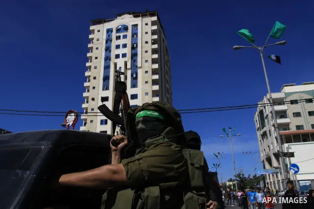 Palestinians keep watch as Hamas militants stand guard in Gaza City on October 18, 2011 as an Israeli-Palestinian prisoner swap deal gets under way. Captive Israeli soldier Gilad Shalit was today freed from five years of...