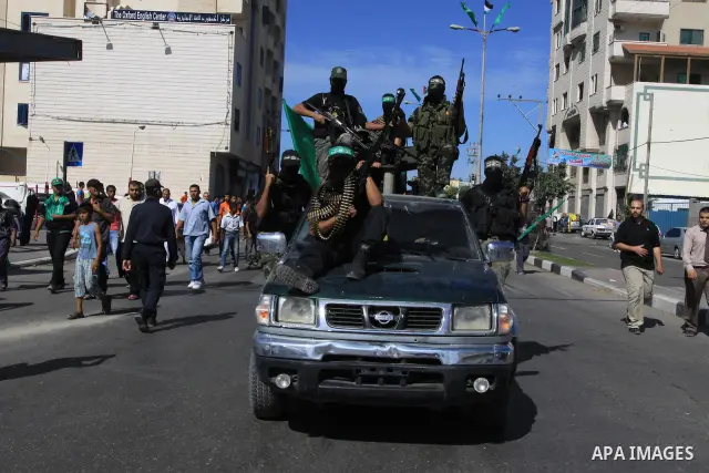 Palestinians keep watch as Hamas militants stand guard in Gaza City on October 18, 2011 as an Israeli-Palestinian prisoner swap deal gets under way. Captive Israeli soldier Gilad Shalit was today freed from five years of...