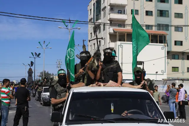 Palestinians keep watch as Hamas militants stand guard in Gaza City on October 18, 2011 as an Israeli-Palestinian prisoner swap deal gets under way. Captive Israeli soldier Gilad Shalit was today freed from five years of...