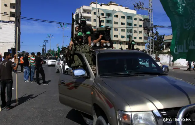 Palestinians keep watch as Hamas militants stand guard in Gaza City on October 18, 2011 as an Israeli-Palestinian prisoner swap deal gets under way. Captive Israeli soldier Gilad Shalit was today freed from five years of...