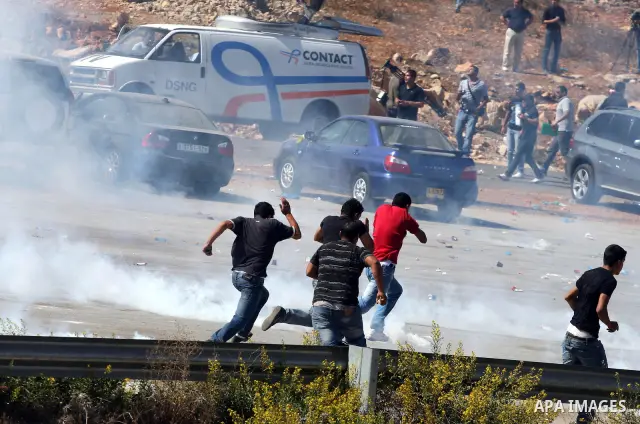 Palestinians run to take cover from tear gas fired by Israeli troops while they wait for released prisoners outside the Ofer prison near the West Bank city of Ramallah on Oct. 18, 2011. Hamas and Israel reached a prison...