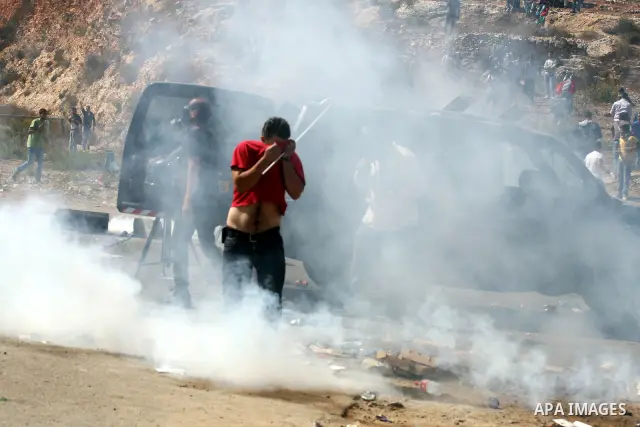 Palestinians run to take cover from tear gas fired by Israeli troops while they wait for released prisoners outside the Ofer prison near the West Bank city of Ramallah on Oct. 18, 2011. Hamas and Israel reached a prison...
