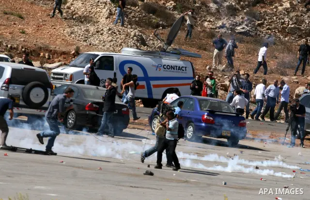 Palestinians run to take cover from tear gas fired by Israeli troops while they wait for released prisoners outside the Ofer prison near the West Bank city of Ramallah on Oct. 18, 2011. Hamas and Israel reached a prison...