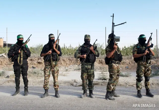 Palestinians keep watch as Hamas militants stand guard in Gaza City on October 18, 2011 as an Israeli-Palestinian prisoner swap deal gets under way. Captive Israeli soldier Gilad Shalit was today freed from five years of...