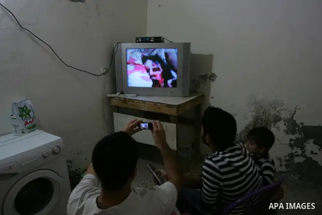 Palestinians watch television news the killing of the Libyan leader,in their home in a refugee camp in Rafah, southern Gaza Strip on October 20, 2011. Head of the military in the city of Tripoli, "Abdel Hakim Belhadj, "...