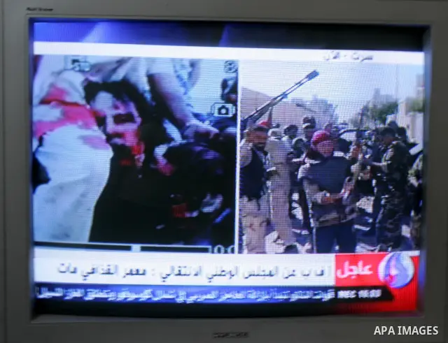 Palestinians watch television news the killing of the Libyan leader,in their home in a refugee camp in Rafah, southern Gaza Strip on October 20, 2011. Head of the military in the city of Tripoli, "Abdel Hakim Belhadj, "...