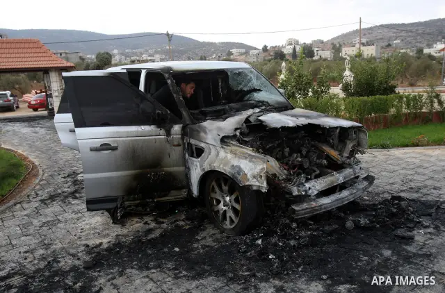 A Palestinian man inspects a burnt car in the village of Beit Furik, near the West Bank town of Nablus, on Oct. 27, 2011. Vandals set fire to a car in a West Bank village, and suspicion has fallen on Jewish settlers. Pal...