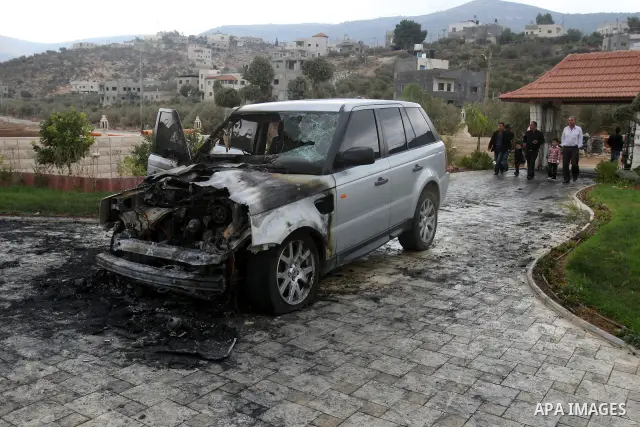 A Palestinian man inspects a burnt car in the village of Beit Furik, near the West Bank town of Nablus, on Oct. 27, 2011. Vandals set fire to a car in a West Bank village, and suspicion has fallen on Jewish settlers. Pal...