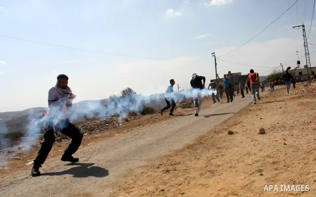 Palestinian protesters run for cover from tear gas canisters fired by Israeli security forces in Kufr Qaddum near the northern West Bank Jewish settlement of Kdumim, Friday ,Friday, Oct. 28, 2011. Palestinians clashed wi...