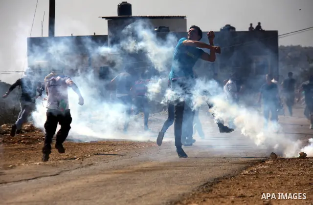 Palestinian man enveloped in tear gas throws a stone at at Israeli security forces in Kufr Qaddum near the northern West Bank Jewish settlement of Kdumim, Friday ,Friday, Oct. 28, 2011. Palestinians clashed with Israeli...