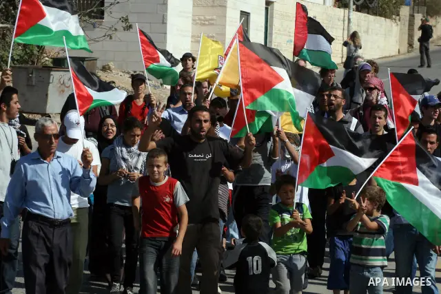 Palestinians wave a national flag in front of Israeli soldiers during clashes following a weekly demonstration against Israeli settlement expansion, in the West Bank village of Nabi Saleh, on October 28, 2011. Photo by I...