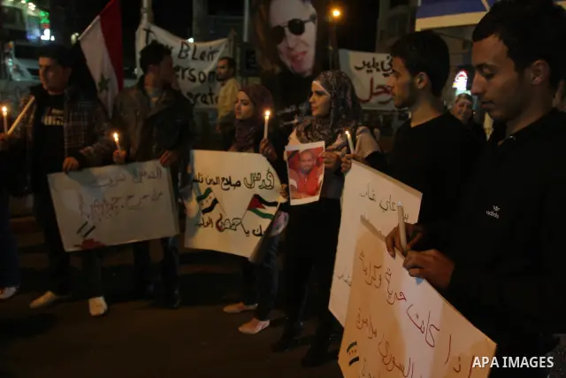 Palestinians hold candles and the Syrian national flag against the Syrian regime and Syrian President Bashar al-Assad in the West Bank city of Ramallah on Oct. 30, 2011. Photo by Issam Rimawi