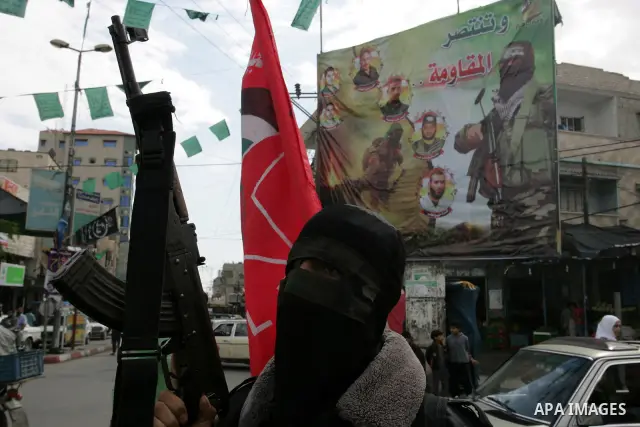A Palestinian Democratic Front for the Liberation of Palestine militant shoots in the air during the funeral of DFLP militant Ahmed Jargon, killed in an Israeli strike on Sunday, in Rafah, southern Gaza Strip, Monday, Oc...