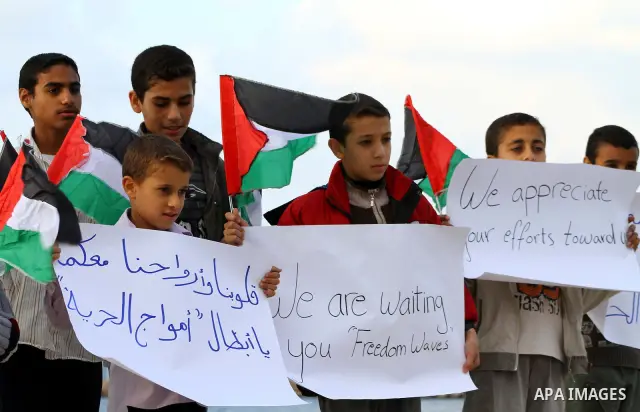 Palestinian children wave national flags during a rally to show their support for a two boat flotilla attempt to reach the Gaza Strip, in the port of Gaza City Friday, Nov. 4, 2011. Israel's military says the navy has bo...