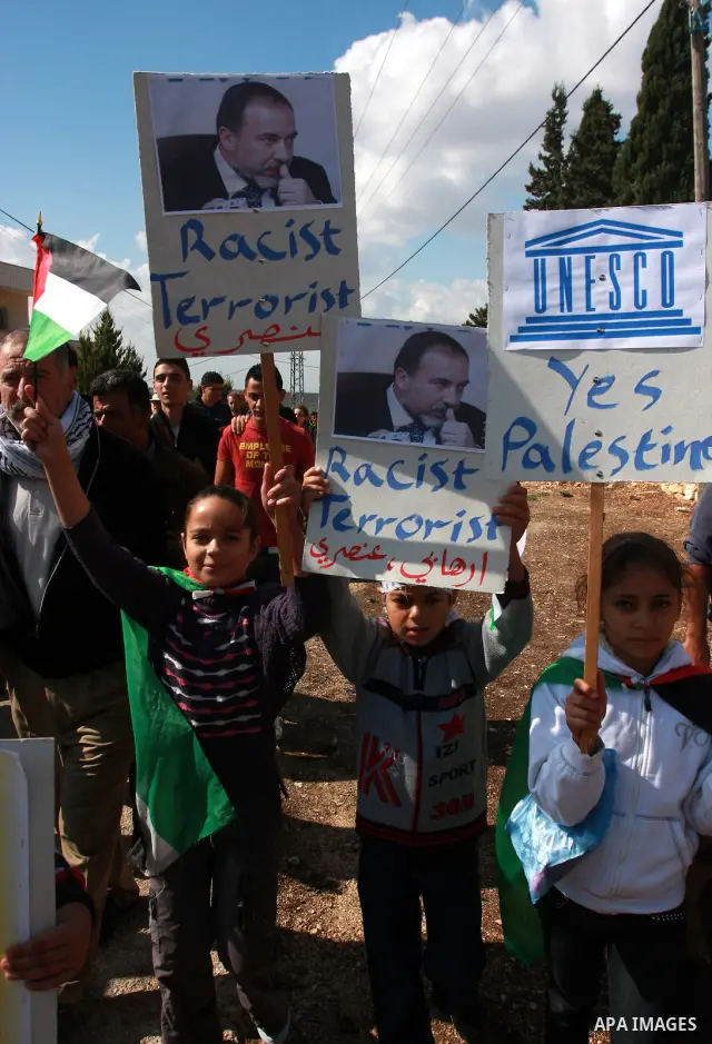 Palestinian demonstrators from the village of Kfar Kadum rally on November 4, 2011 in the Israeli-occupied West Bank as they hold pictures of Palestinian president Mahmud Abbas and Israeli Foreign Minister Avigdor Liberm...