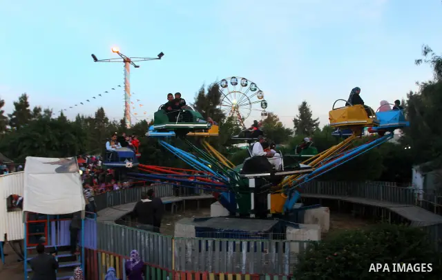 Palestinians enjoy a ride in an amusement park, during Eid al-Adha in Gaza City, Nov. 9, 2011. Muslims worldwide celebrate Eid al-Adha, or the Feast of the Sacrifice, with the sacrificial killing of livestock to commemor...