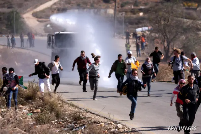 Palestinian protesters try to avoid tear gas shoot by Israeli soldiers during clashes between Israeli security forces and Palestinian demonstrators at a weekly protest in the West Bank village of Nabi Saleh, near Ramalla...