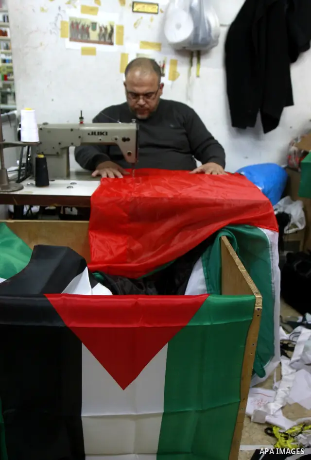 A Palestinian man sews his national flag at his workshop in the West Bank city of Nablus, Monday, Nov. 14, 2011. during the preparation to mark the anniversary of the declaration of independence state of Palestinian on N...