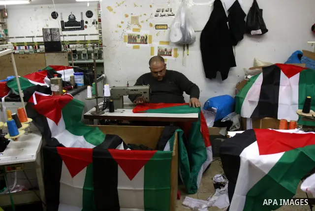 A Palestinian man sews his national flag at his workshop in the West Bank city of Nablus, Monday, Nov. 14, 2011. during the preparation to mark the anniversary of the declaration of independence state of Palestinian on N...