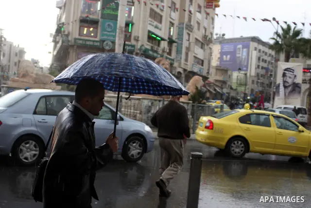 Palestinians walk in a street during heavy rains in the West Bank city of Ramallah on Nov. 14,2011. Photo by Issam Rimawi
