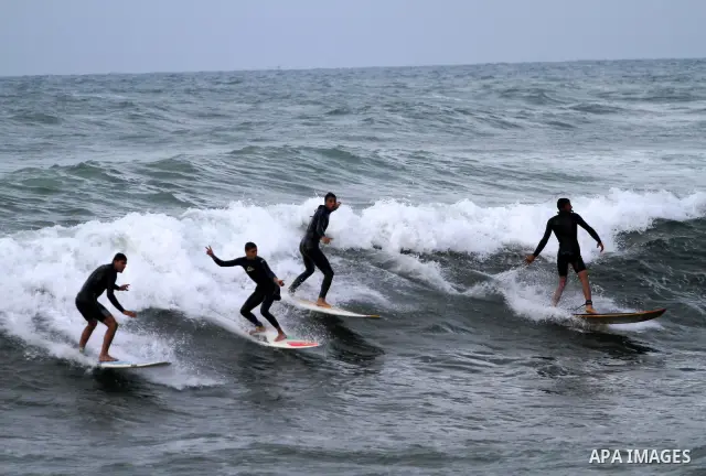 Palestinian youths surf in the Mediterranean Sea off the coast of Gaza City, as a cold and windy weather hits Gaza Strip, on Nov. 16,2011. Photo by Mohammed Asad