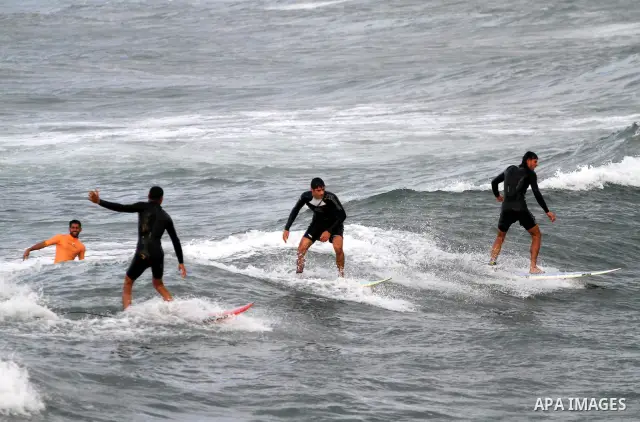 Palestinian youths surf in the Mediterranean Sea off the coast of Gaza City, as a cold and windy weather hits Gaza Strip, on Nov. 16,2011. Photo by Mohammed Asad