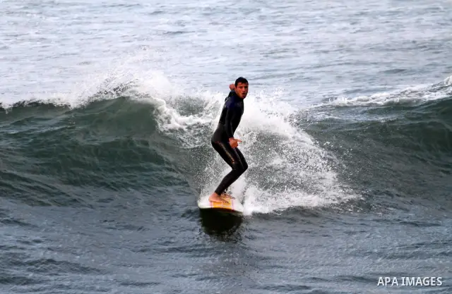 Palestinian youths surf in the Mediterranean Sea off the coast of Gaza City, as a cold and windy weather hits Gaza Strip, on Nov. 16,2011. Photo by Mohammed Asad