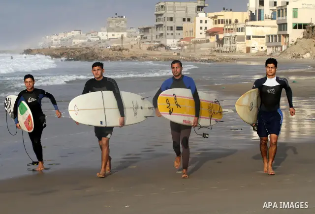 Palestinian youths surf in the Mediterranean Sea off the coast of Gaza City, as a cold and windy weather hits Gaza Strip, on Nov. 16,2011. Photo by Mohammed Asad