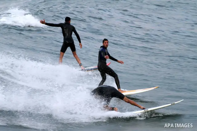 Palestinian youths surf in the Mediterranean Sea off the coast of Gaza City, as a cold and windy weather hits Gaza Strip, on Nov. 16,2011. Photo by Mohammed Asad