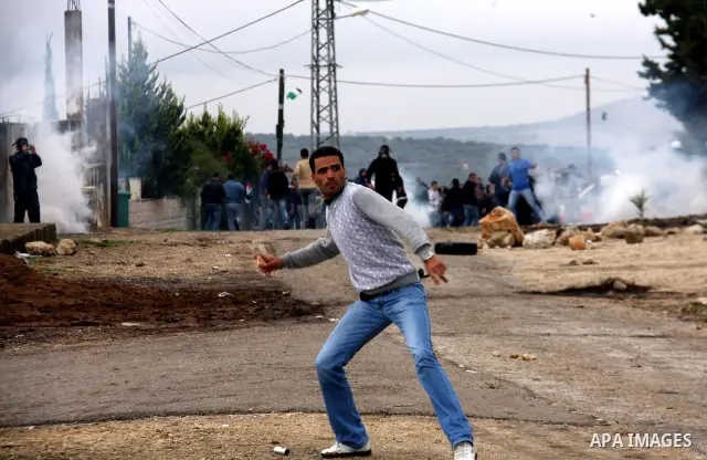 A Palestinian demonstrator throws a stone at at Israeli security forces , who are seeking access to their land near Kufr Qaddum, near the northern West Bank Jewish settlement of Kdumim, Friday, Nov. 18, 2011. Photo by Wa...