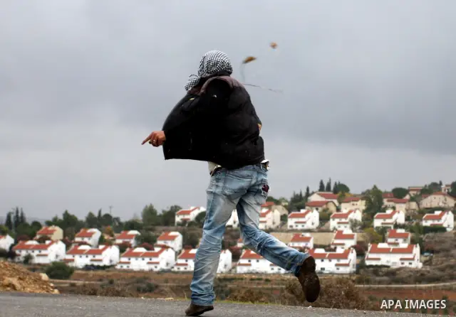 A Palestinian youth uses a sling to throw a stone toward Israeli soldiers during clashes at a weekly protest in the West Bank village of Nabi Saleh, near Ramallah November 18, 2011. Photo by Issam Rimawi