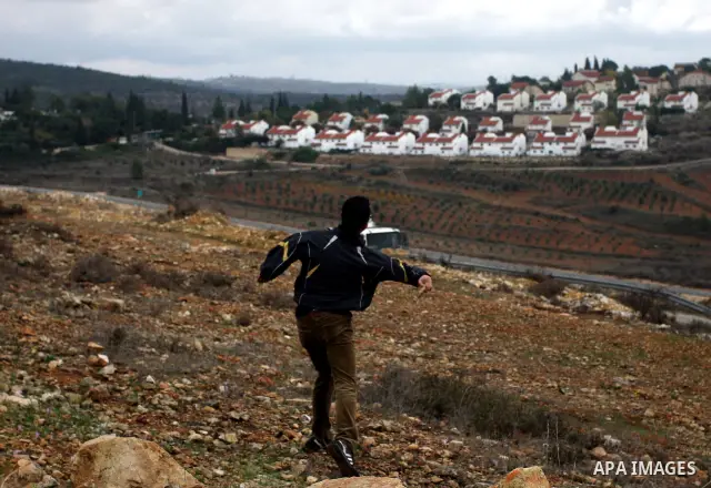 Palestinian youths and Israeli troops clash following a weekly demonstration against Israeli settlement expansion (background), in the West Bank village of Nabi Saleh, on November 18, 2011. Photo by Issam Rimawi